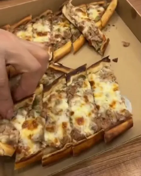 Slices of pide being packed into a takeaway box