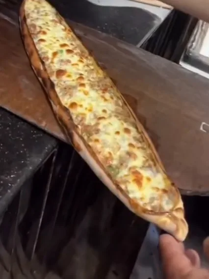 A freshly baked cheese pide being brushed