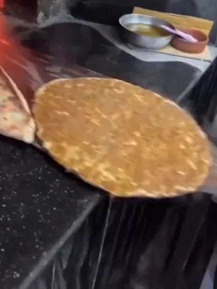 A lahmacun coming out of the oven on the peel